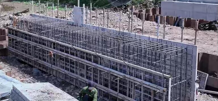 Tường dài đang thi công bằng cốp pha nhựa, tấm xếp sẵn bên cạnh